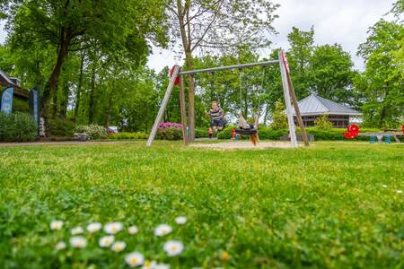 Kinder auf der Schaukel auf einem Spielplatz im Ferienpark EuroParcs Maasduinen