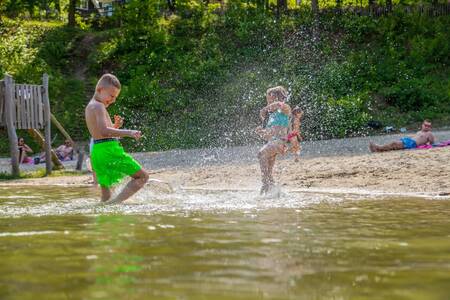 Kinder spielen im Wasser des Strandpools des Ferienparks EuroParcs Maasduinen