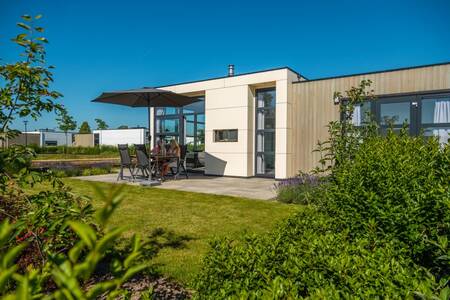 Im Garten eines Chalets im Ferienpark EuroParcs Marina Strandbad sitzen Menschen auf Gartenmöbeln