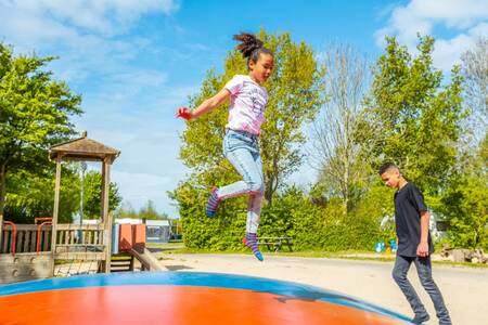 Kinder springen auf dem Lufttrampolin auf dem Spielplatz im Ferienpark EuroParcs Molengroet