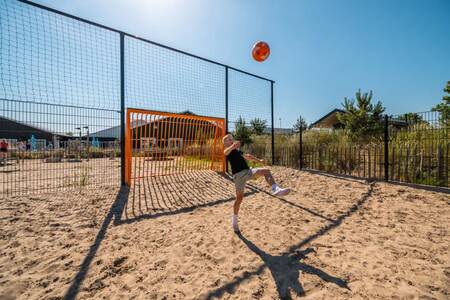 Junge spielt Fußball auf dem Sportplatz im Ferienpark EuroParcs Poort van Zeeland