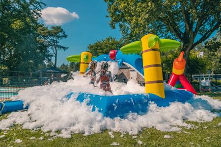 Kinder spielen im Schaum auf einem Luftkissen im Ferienpark EuroParcs Reestervallei