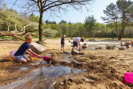 Auf dem Naturspielplatz im Ferienpark EuroParcs Ruinen spielen Kinder mit Sand und Wasser