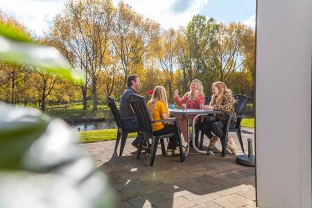 Familie am Tisch im Garten eines Ferienhauses im Ferienpark EuroParcs Spaarnwoude