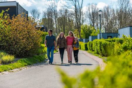 Die Familie geht zwischen den Ferienhäusern im Ferienpark EuroParcs Spaarnwoude spazieren