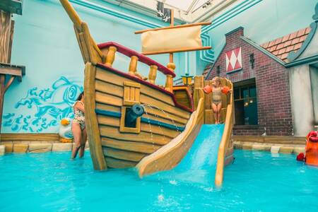 Kind auf einer kleinen Rutsche im Schwimmbad des Ferienparks EuroParcs Zuiderzee