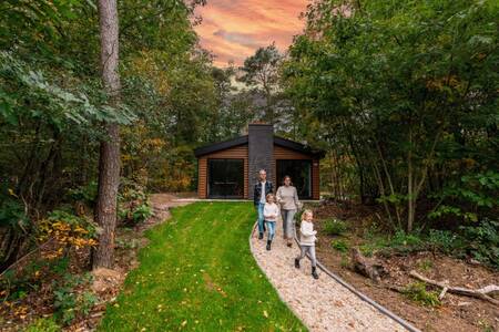 Familienspaziergang vor einem Chalet im Ferienpark EuroParcs de Wiltzangh