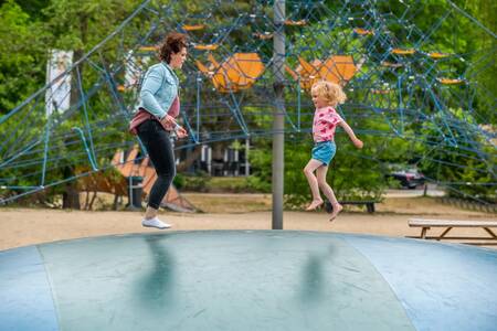 Mutter und Kind springen auf dem Lufttrampolin auf dem Spielplatz - Ferienpark EuroParcs de Zanding