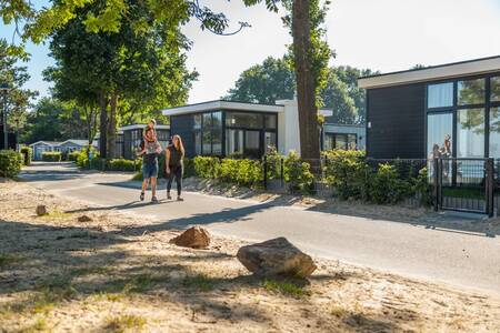 Die Familie geht vor einigen Ferienhäusern im Ferienpark Europarcs Bad Hoophuizen spazieren