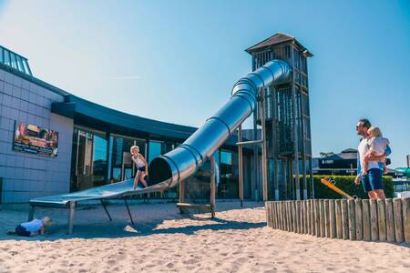 Kind rutscht die Rutsche auf einem Spielplatz im Europarcs EuroParcs Zilverstrand hinunter