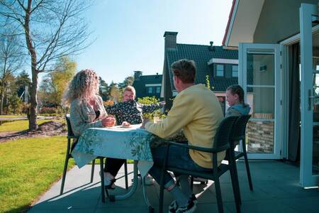 Familie an einem Tisch im Garten eines Ferienhauses im Ferienpark Europarcs de Achterhoek