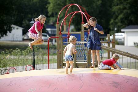 Kinder springen auf dem Lufttrampolin auf einem Spielplatz im Ferienpark Familiehuis Nunspeet