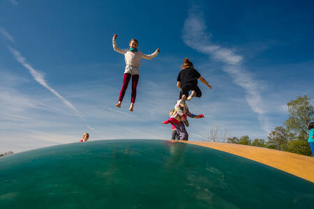 Kinder springen auf dem Lufttrampolin auf einem Spielplatz im Ferienpark Wilsumer Berge