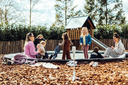2 Frauen mit Kindern auf dem Trampolin auf dem Spielplatz im Ferienpark Het Wylde Pad