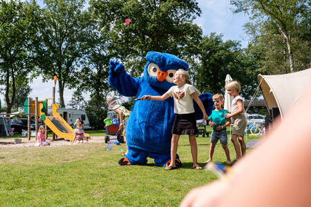 Cobus das Eulenmaskottchen von Camping Village de Zandstuve mit Kindern auf dem Spielplatz