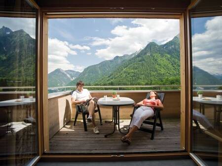 2 Personen entspannen auf dem Balkon einer Wohnung im Landal Alpen Chalet Matin