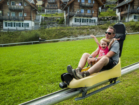 Vater und Tochter beim Rodeln auf der Rodelbahn der Landal Alpen Chalets Katschberg