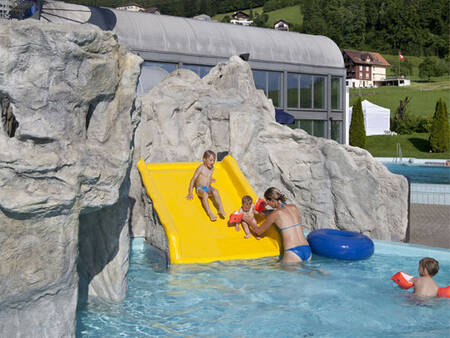 Kinder rutschen im Planschbecken des Landal Alpen Resort Vierwaldstättersee die Rutsche hinunter