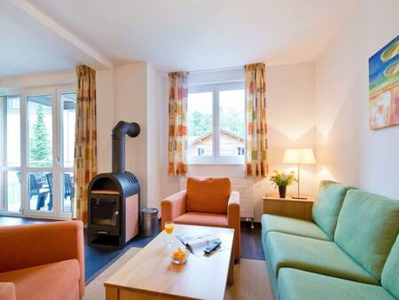Wohnzimmer mit Holzofen einer Wohnung im Landal Alpen Resort Vierwaldstättersee