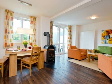 Wohnzimmer mit Tisch und Holzofen in einer Wohnung im Landal Alpen Resort Vierwaldstättersee