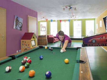 Ein Junge spielt Billard in der Spielhalle des Ferienparks Landal Bad Kleinkirchheim