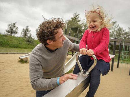 Mädchen auf einer Wippe auf einem Spielplatz im Ferienpark Landal Beach Park Ebeltoft