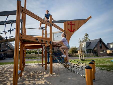 Kinder klettern auf einem Spielgerät auf einem Spielplatz im Ferienpark Landal Berger Duinen