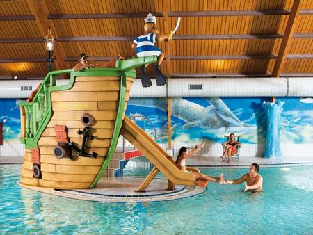 Ein Kind rutscht die Rutsche im Hallenbad des Ferienparks Landal Coldenhove hinunter