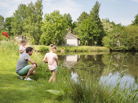 Eine Familie fischt im Wasser des Ferienparks Landal De Bloemert