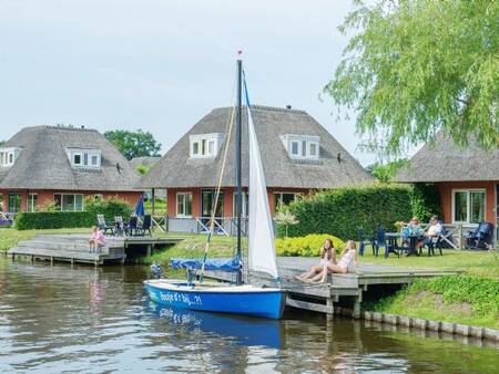 Ein Boot liegt am Steg eines Ferienhauses im Ferienpark Landal De Bloemert