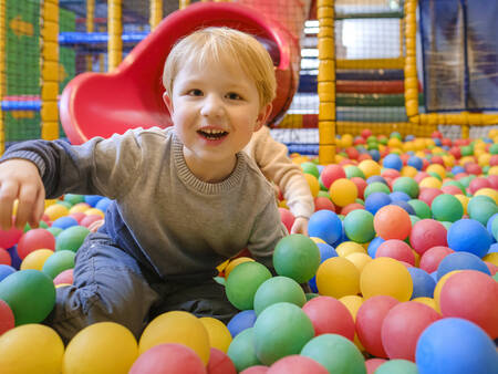 Kinder spielen im Bällebad des Indoor-Spielplatzes im Ferienpark Landal De Hellendoornse Berg