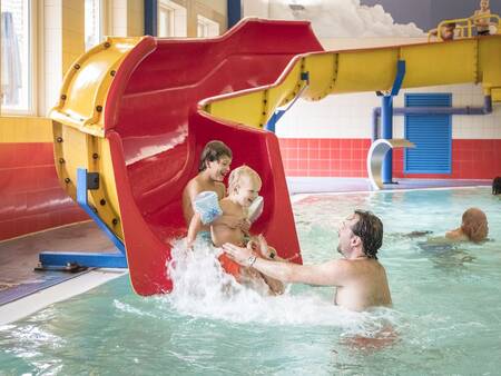 Kinder rutschen die Rutsche im Schwimmbad des Ferienparks Landal De Hellendoornse Berg hinunter