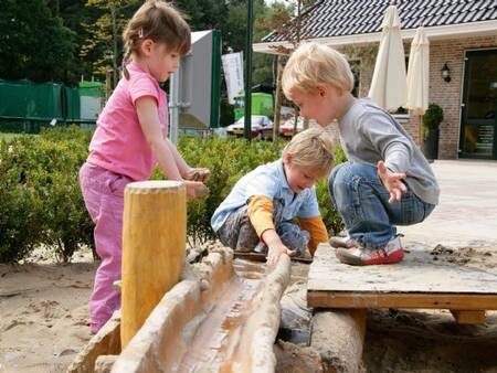 Auf dem Spielplatz des Ferienparks Landal De Hellendoornse Berg spielen Kinder mit Wasser