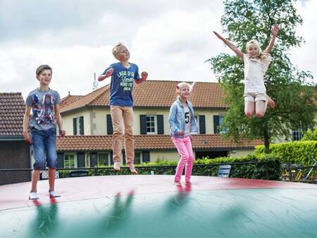 Kinder springen auf dem Lufttrampolin auf einem Spielplatz im Ferienpark Landal Duc de Brabant
