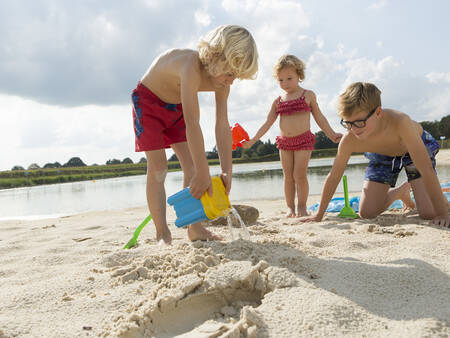 Kinder spielen am Strand des Freizeitsees des Ferienparks Landal Dwergter Sand