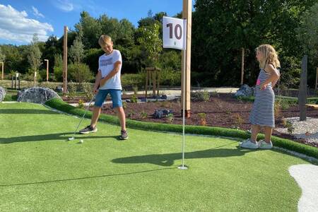 Kinder spielen Golf auf dem Minigolfplatz im Ferienpark Landal Forest Resort Your Nature