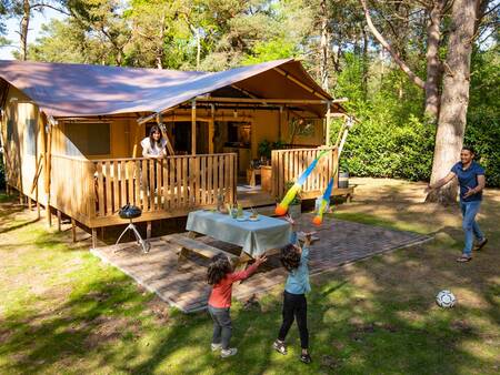 Familie spielt in ihrem Safarizelt im Ferienpark Landal Gooise Heide