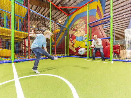 Vater und Sohn spielen Fußball im Indoor-Spielparadies des Ferienparks Landal Hochwald