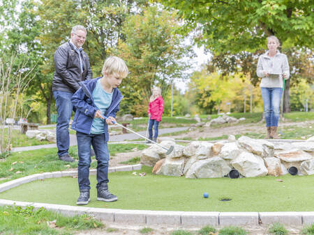 Eine Familie spielt Golf auf dem Minigolfplatz des Ferienparks Landal Hochwald