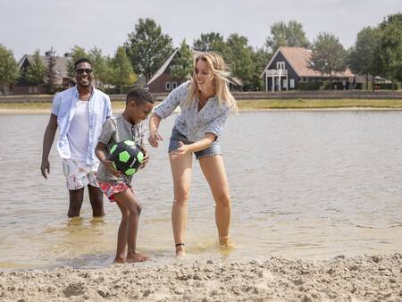 Die Familie spielt im Wasser des Freizeitsees im Ferienpark Landal Hof van Saksen