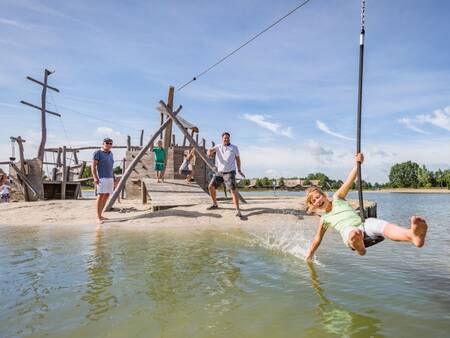 Kinder spielen auf dem Spielplatz am Freizeitsee von Landal Hof van Saksen