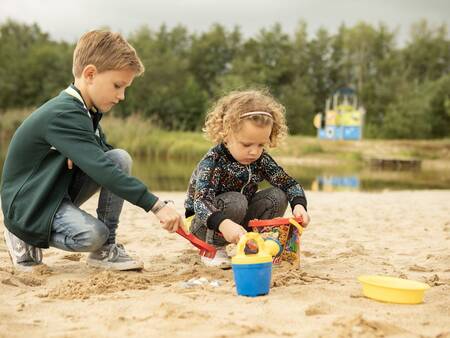 Kinder spielen am Strand des Erholungssees des Ferienparks Landal Hunerwold State