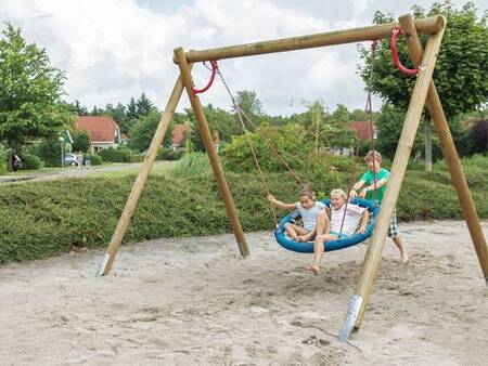 Kinder auf einer Schaukel auf einem Spielplatz im Ferienpark Landal Hunerwold State