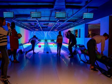 Leute, die im Schein der dunklen Bowlingbahn von Landal Landgoed 't Loo bowlen