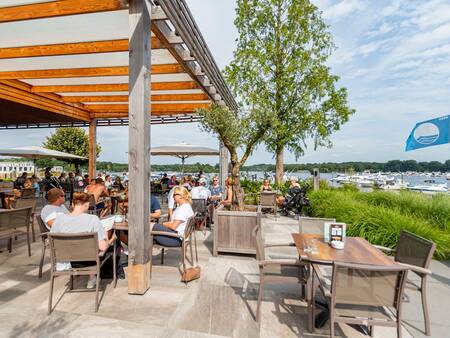 Menschen auf der Terrasse des Beachclub Leukermeer im Ferienpark Landal Marina Resort Well