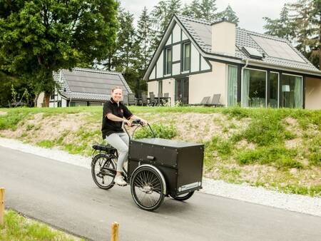 Frau mit Lastenrad vor Ferienhäusern im Ferienpark Landal Mont Royal