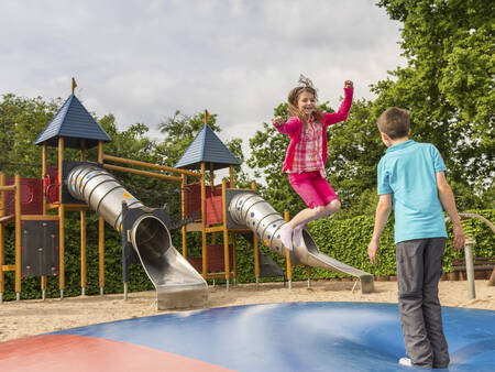 Kinder springen auf dem Lufttrampolin auf einem Spielplatz im Ferienpark Landal Mont Royal