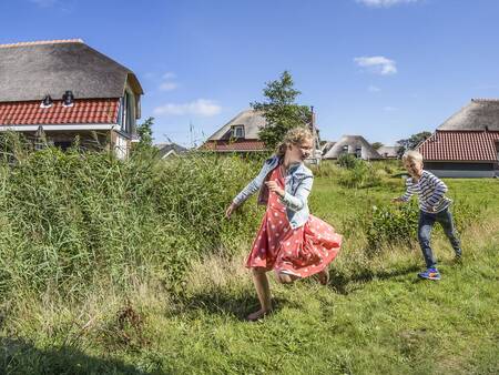 Kinder spielen auf dem Rasen der Ferienhäuser im Ferienpark Landal Sluftervallei vakantie