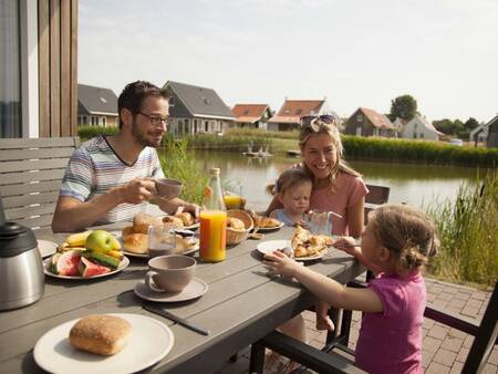 Eine Familie isst im Garten des Ferienparks Landal Strand Resort Nieuwvliet-Bad
