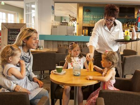 Eine Familie genießt einen Drink im Restaurant De Smokkelaar im Landal Strand Resort Nieuwvliet-Bad